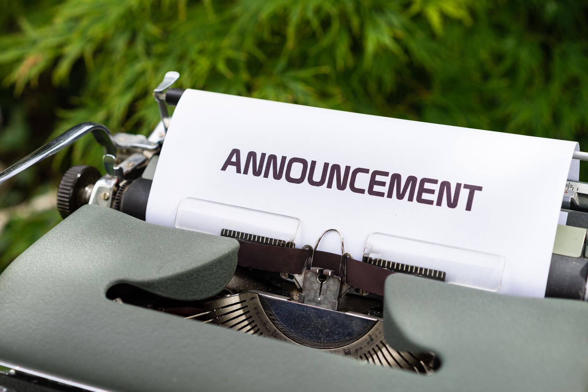 A vintage typewriter outdoors, a sheet of paper rolled in reading ANNOUNCEMENT